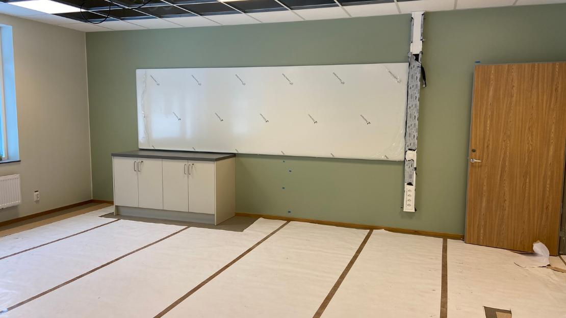 Klassrum för årskurs F-3 på Högvadskolan, med en grön fondvädd och en vit whiteboard på väggen.