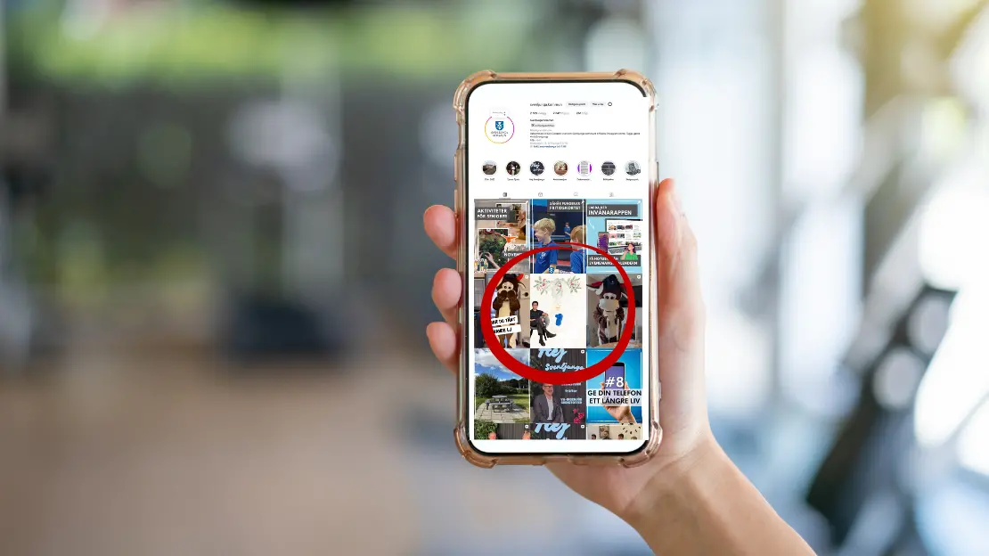 En suddig bakgrund. I förgrunden syns en hand som håller i en mobil. På skärmen syns profilsidan för kommunens instagram.