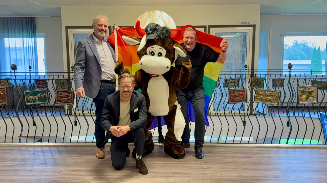 Tjuris, Johan och Patrik står med Pride-flaggan. Sebastian står på ett knä framför.