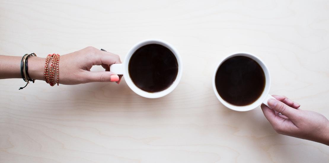 två olika händer som håller i kaffekoppar med kaffe i 