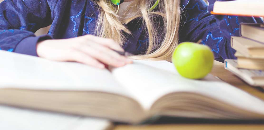 någon som sitter och läser en bok och äter äpple sedan lagt de på ena sidan av boken 