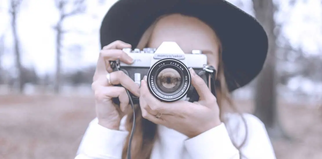 person i stor svart hatt fotograferar