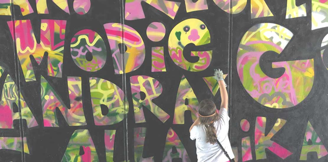 ung person står framför en färgglad grafittivägg