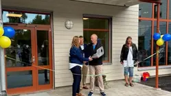 Politiker och tjänstepersoner står framför ingång till skolan som är pyntat med ballonger och band.