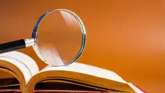 En uppslagen bok med ett förstoringsglas på