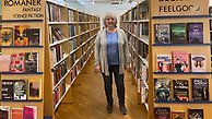 Bibliotekarie Mary-Ann står mellan två bokhyllor.