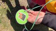 En hand som visar upp en medalj med karaktärerna Kurran och Pigan,