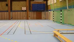 Idrottshall där man ser ett fotbollsmål och basketkorg.